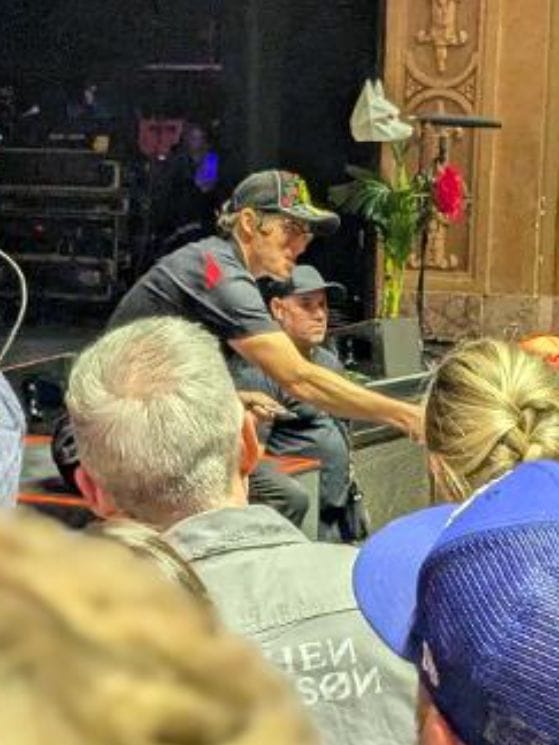 Stephen Wilson Jr. reaching out to connect with fans after the show, leaning down from near the stage while audience members look on
